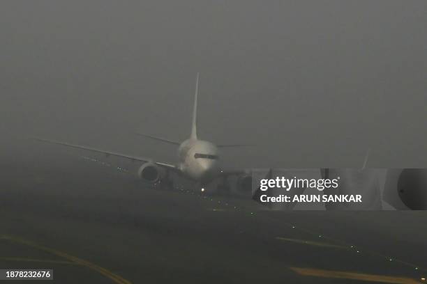 An aircraft prepares to take off amid dense fog on a cold winter morning at Indira Gandhi International Airport in New Delhi on December 27, 2023.