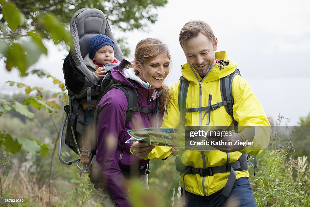 Young family hiking, looking at the map together