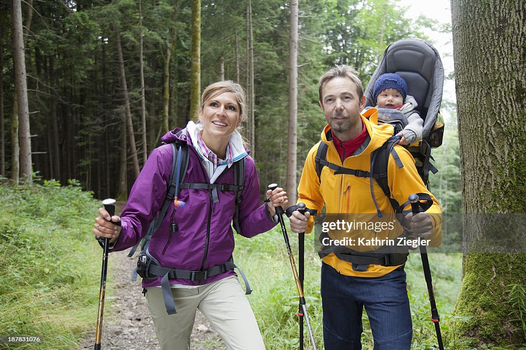 Happy young family hiking, girl in baby carrier