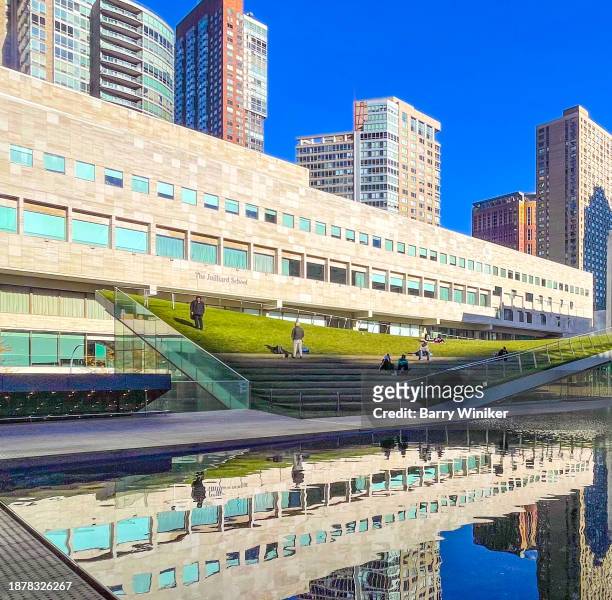 reflection in pool of people on slanted lawn and juilliard school, nyc - new york basks in sunny indian summer day stock-fotos und bilder