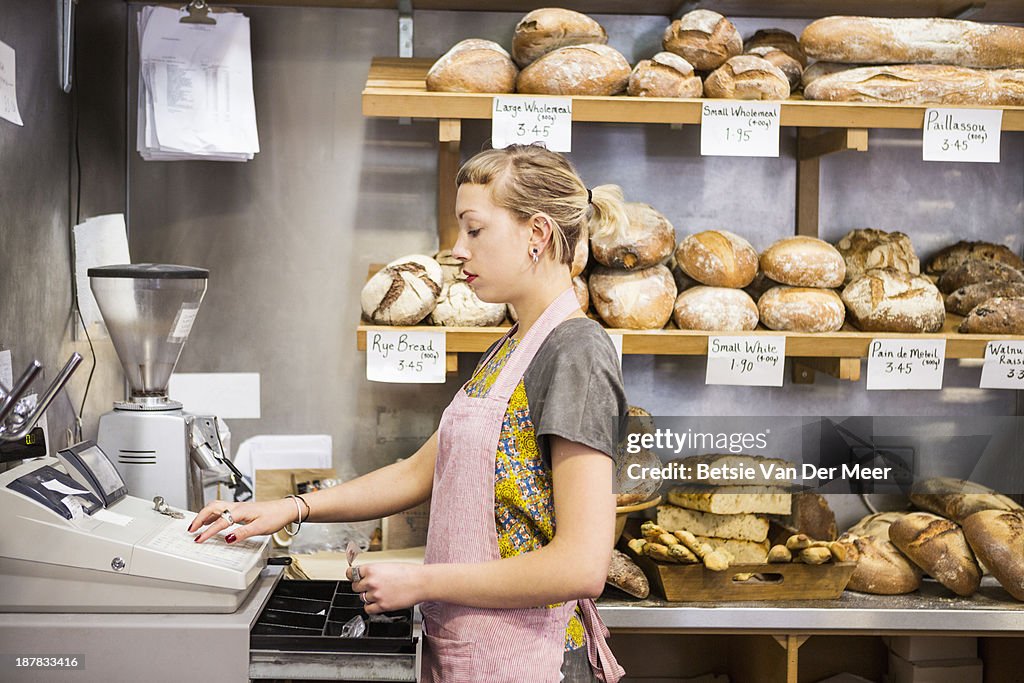 Shop assistant opening till in shop.