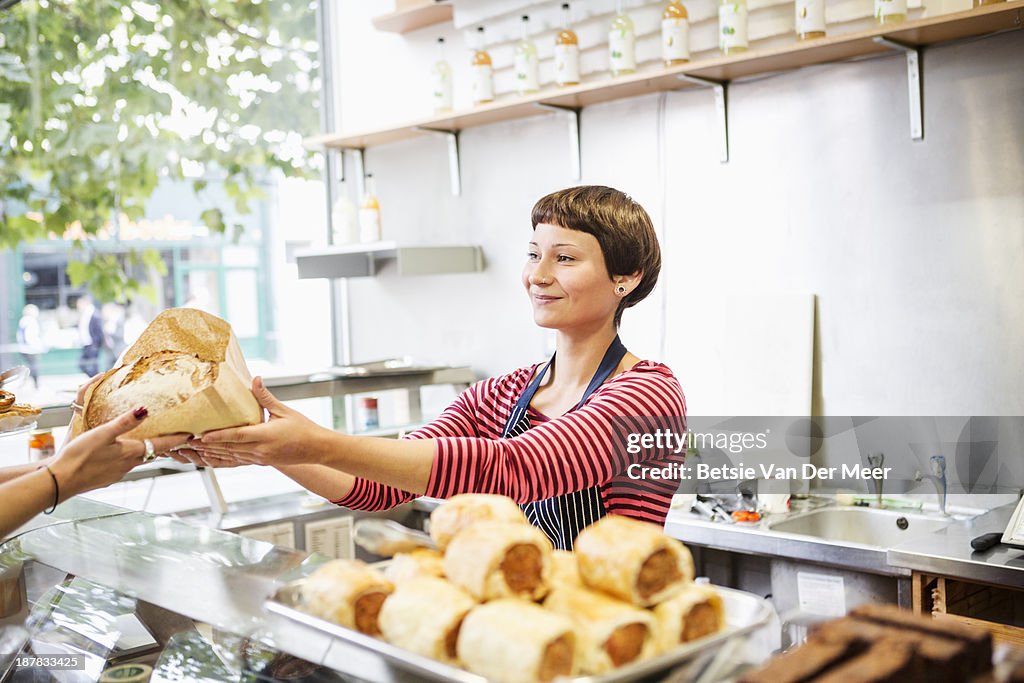Shop assistant handing bread to customer.