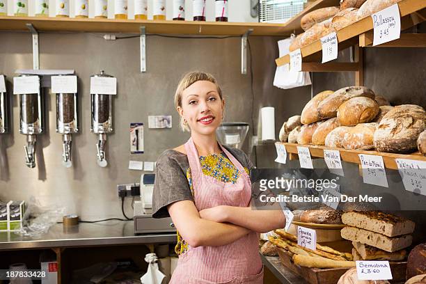 shopkeeper in front of bread display in shop. - bakery fotografías e imágenes de stock