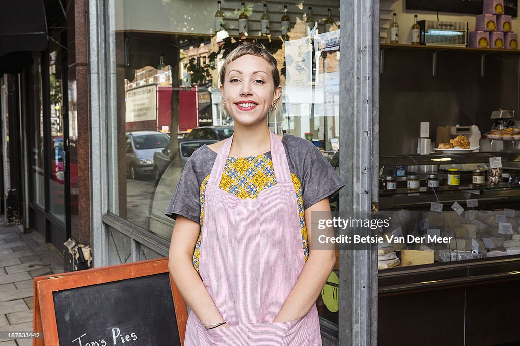 Female entrepreneur in front of deli shop.