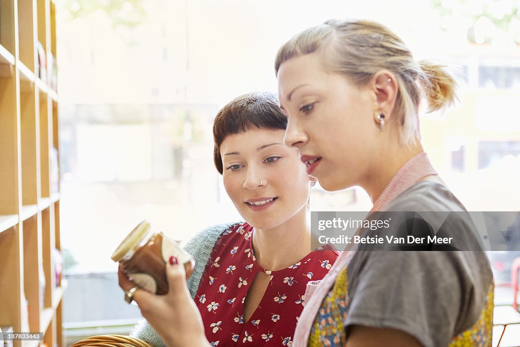 Shop assistant and customer looking at food label.