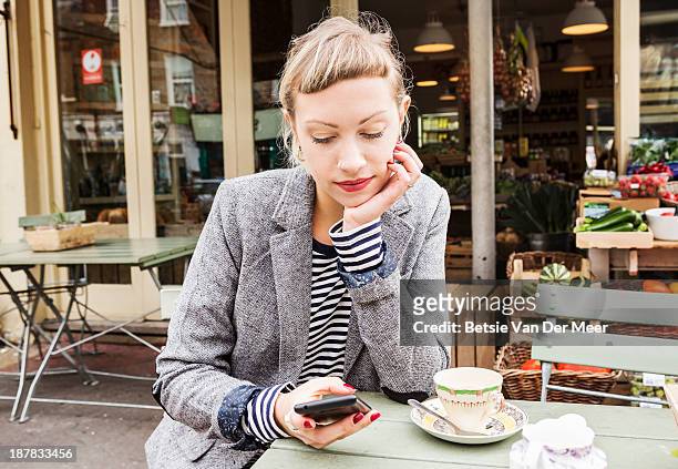 woman checking phone at outdoor cafe farm shop. - franja imagens e fotografias de stock