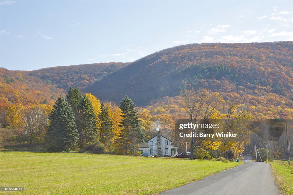 Country road with house and mountains in autumn