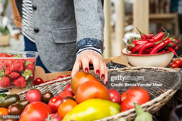 close up of hand picking tomato from basket. - food in market stock-fotos und bilder