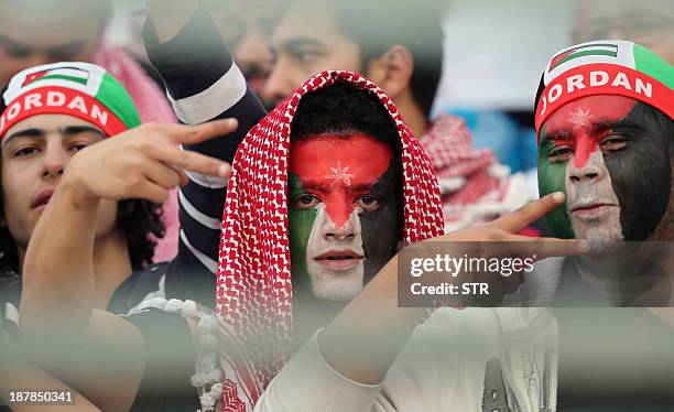 Jordanese fans with their faces painted in the colours of their national flag pose for a photo as they cheer on their team before the FIFA 2014 World...