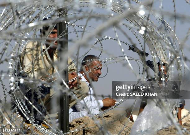 Relatives wait for the release of Iraqi prisoners while sitting behind barbed wires outside the Abu Ghraib prison, on the outskirts of Baghdad 01...