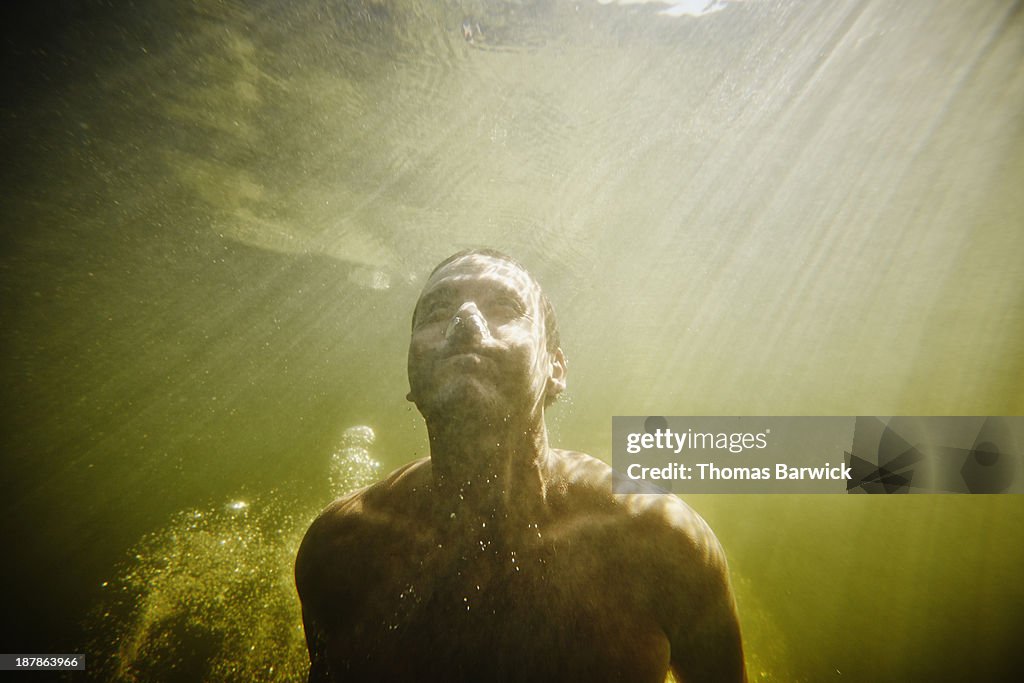 Man underwater swimming towards surface of water