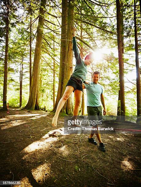 woman walking on slackline in woods - acrobatic activity stock-fotos und bilder