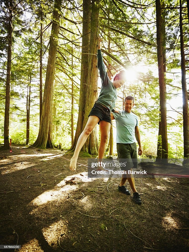 Woman walking on slackline in woods