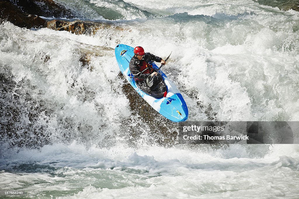 Man kayaking off waterfall in white water rapids