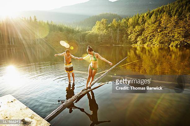 Couple balancing on logs in lake