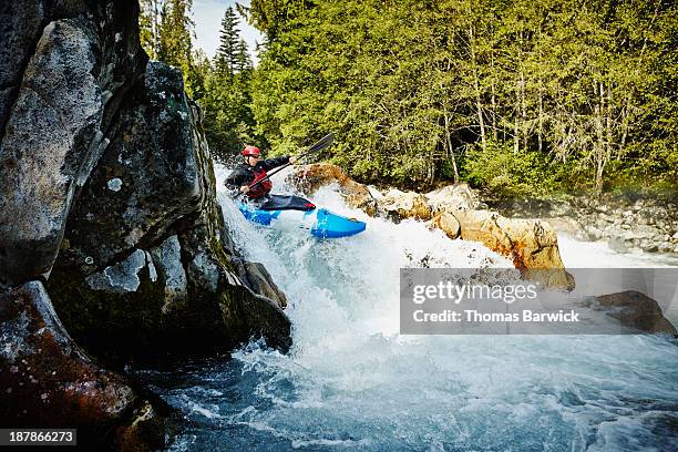 man kayaking between rocks in white water rapids - white water kayaking stock pictures, royalty-free photos & images