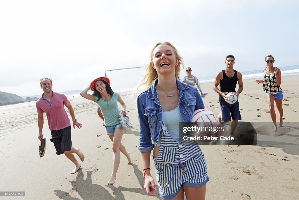 Group of young adults on beach with ball and goal