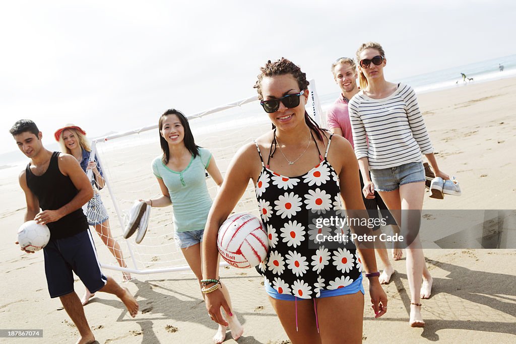 Group of young adults on beach with ball and goal