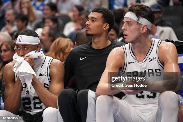 Malaki Branham, Victor Wembanyama, and Zach Collins of the San Antonio Spurs sit on the bench during the second half of the game against the Dallas...