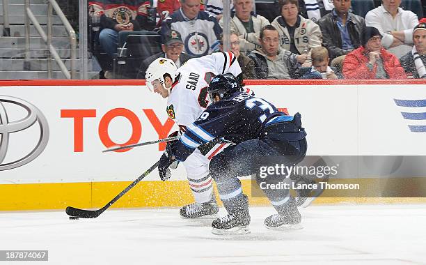 Brandon Saad of the Chicago Blackhawks plays the puck along the boards as Tobias Enstrom of the Winnipeg Jets defends during third period action at...