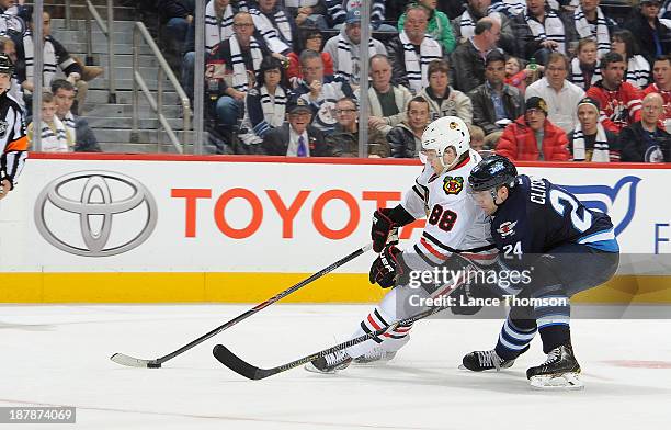 Patrick Kane of the Chicago Blackhawks plays the puck towards the net as Grant Clitsome of the Winnipeg Jets defends from behind during third period...