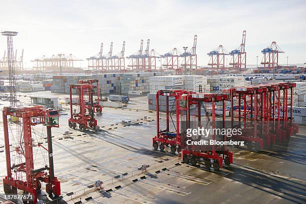 Straddle carriers stand on the dockside beside the Maersk Mc-Kinney Moeller Triple-E Class container ship, operated by A.P. Moeller-Maersk A/S, in...