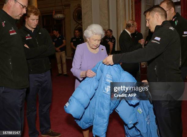 Britain's Queen Elizabeth II examines a jacket presented by a member of Team USA, as her grandson Prince Harry looks on during a reception at...