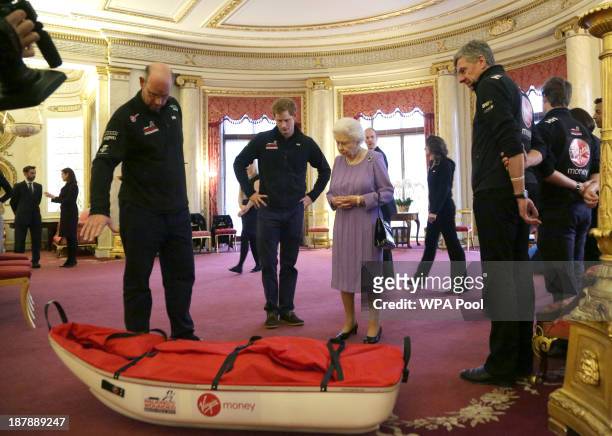 Ed Parker co-Founder of Walking with the Wounded and team mentor of Team USA, Prince Harry and Queen Elizabeth II examine a pulk belonging to TEAM UK...