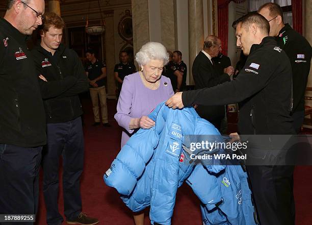 Queen Elizabeth II examines a jacket presented by a member of Team USA, as Ed Parker , co-Founder of Walking with the Wounded and Prince Harry look...
