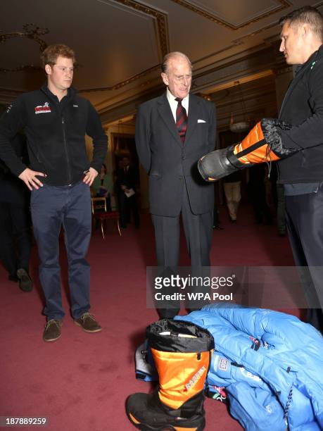 Prince Philip, Duke of Edinburgh and Prince Harry look at a boot shown to them by a member of Team USA during a reception to meet the three teams of...