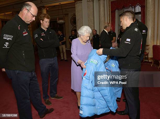 Queen Elizabeth II examines a jacket presented by a member of Team USA, as Ed Parker , co-Founder of Walking with the Wounded and Prince Harry look...