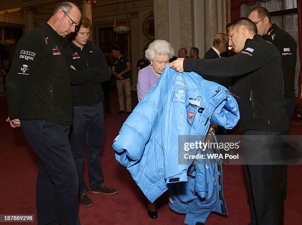 Queen Elizabeth II examines a jacket presented by a member of Team USA, as Ed Parker , co-Founder of Walking with the Wounded and Prince Harry look...