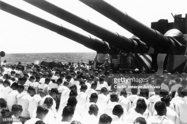 On the American battleship USS South Dakota, the crew bows their heads as Chaplain Lindner reads a benediction in honor of sailors killed in action...