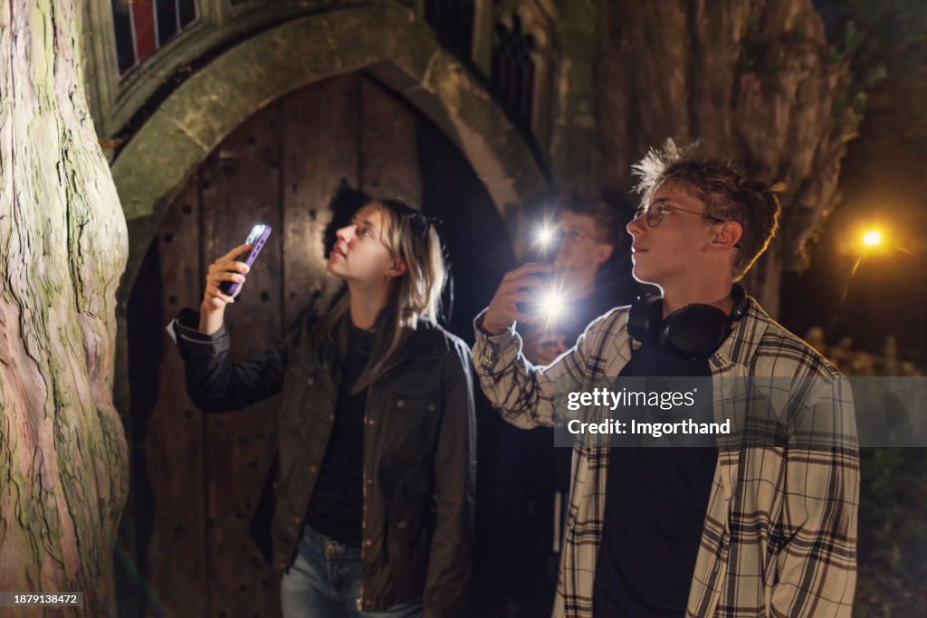 Teenagers sightseeing beautiful church door in village of Stow-on-the-Wold at night