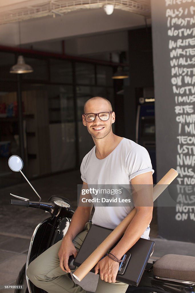 Smiling businessman sitting on scooter