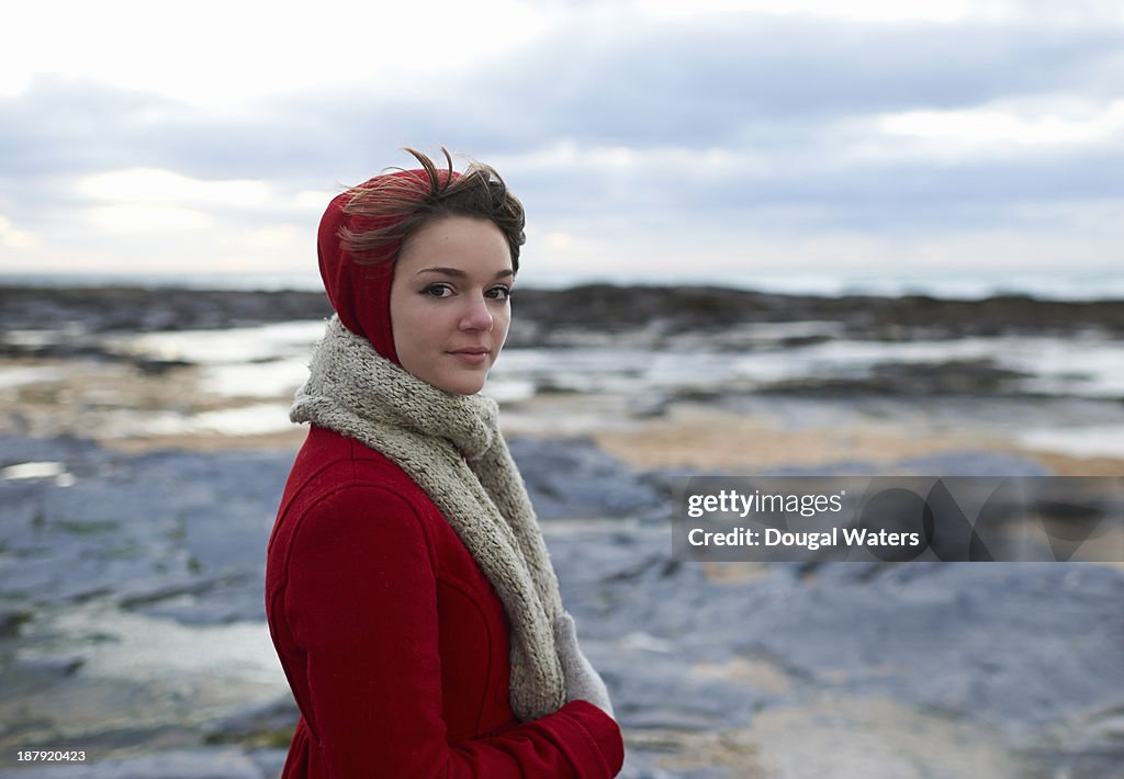 Woman on coastline in red coat.