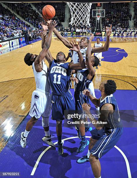 Players Wesley Iwundu and Nino Williams of the Kansas State Wildcats go up for a rebound against guard Shawn Glover of the Oral Roberts Golden Eagles...