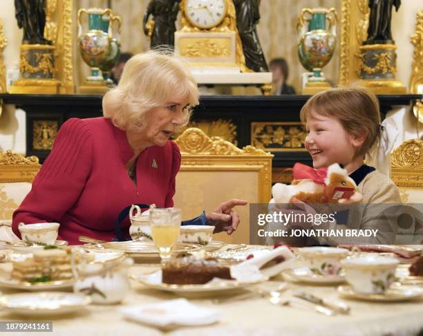 Britain's Queen Camilla presents seven-year-old Olivia Taylor , a blind schoolgirl with a brain tumour, with a corgi soft toy as a Christmas present...