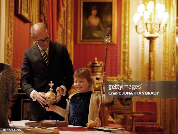 Windsor Castle Superintendent Duncan Dewar offers replicas of the Coronation Orb and Sceptre to seven-year-old Olivia Taylor , a blind schoolgirl...