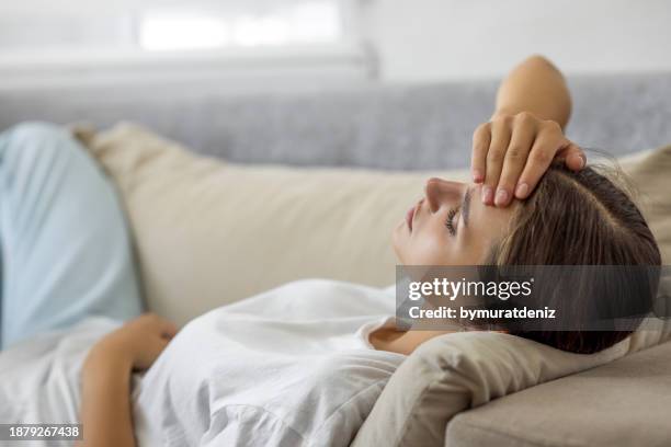 woman laying on sofa eyes closed feeling unwell - tired stock pictures, royalty-free photos & images