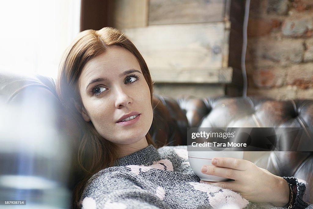 Woman relaxing on sofa with coffee