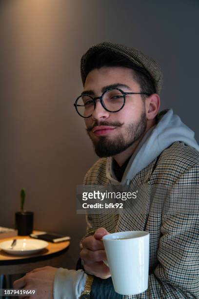 young handsome man in eyewear spending free time in coffee shop. - time life authors stock pictures, royalty-free photos & images