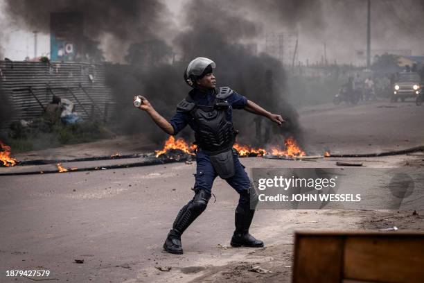 Police officer throws a flash bang grenade during an opposition demonstration in Kinshasa on December 27, 2023. Police were deployed in the...