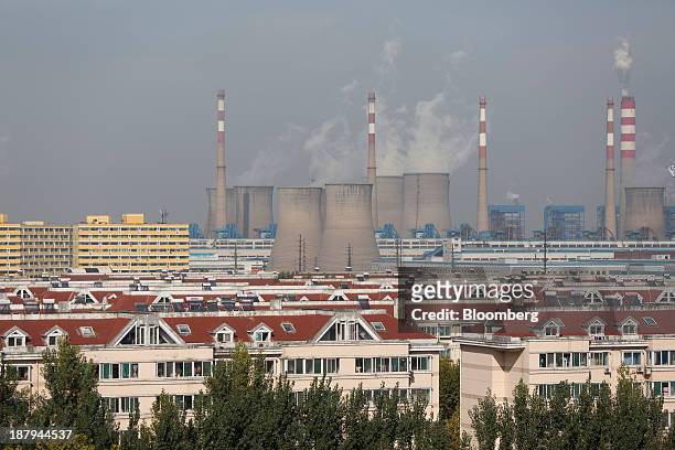 Residential buildings stand in the foreground as vapor rises from a power plant, background, at the China Hongqiao Group Ltd. Aluminum smelting...