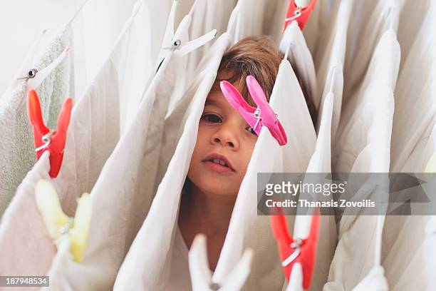 small boy hiding in the laundry - wäscheleine stock-fotos und bilder