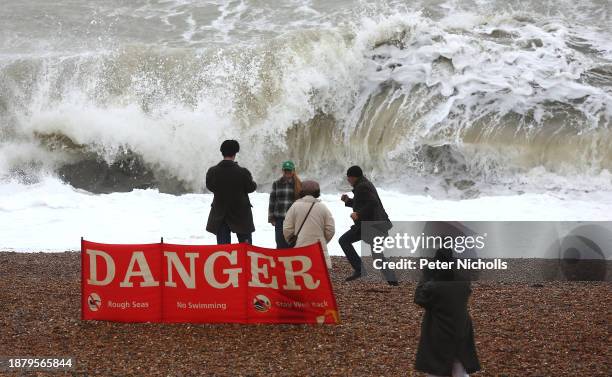 People walk on the beach at high tide, during strong winds on December 27, 2023 in Brighton, United Kingdom. The Met Office issued yellow wind...