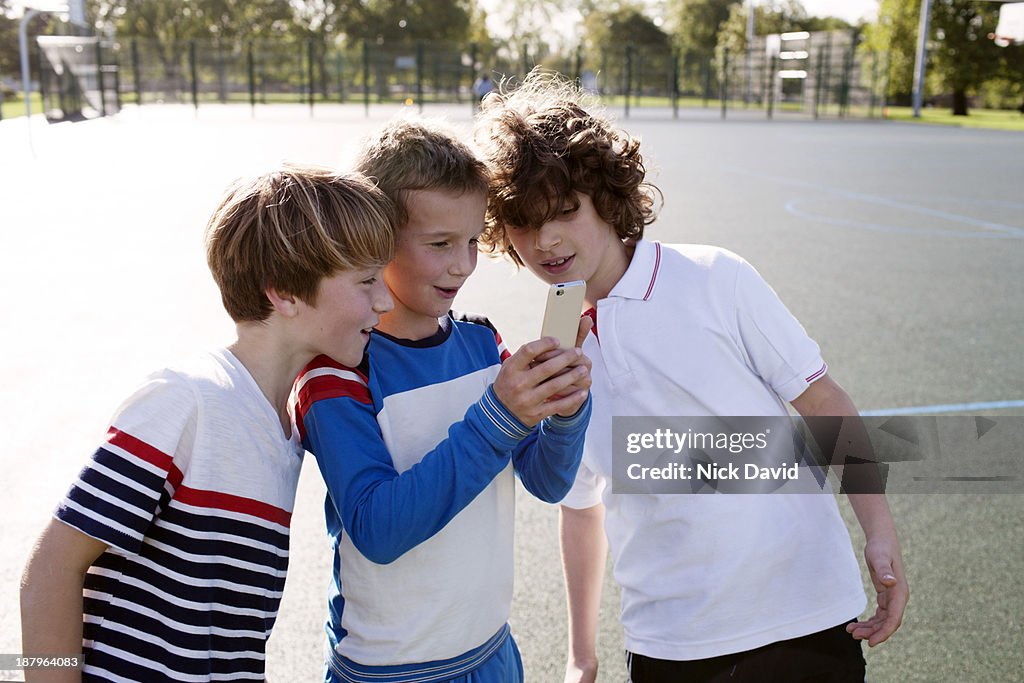 Boys playing outside using mobile phone
