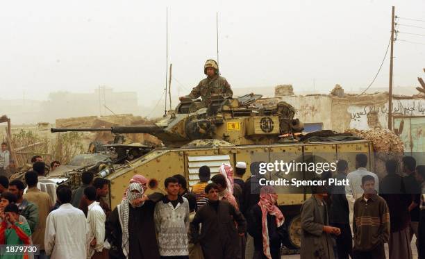 Children and men stand next to a British tank while waiting for the distribution of food and water March 27, 2003 in the Iraqi city of Al Zubaya,...