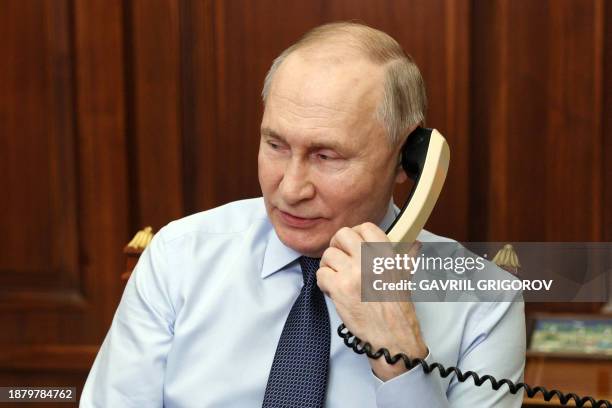 In this pool photograph distributed by Russian state agency Sputnik, Russia's President Vladimir Putin speaks on the phone with Nikita...