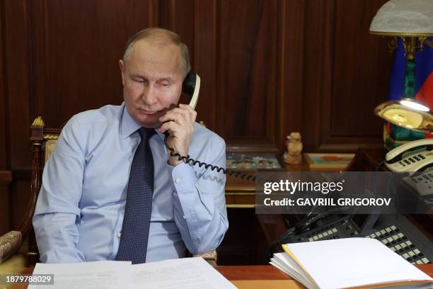 In this pool photograph distributed by Russian state agency Sputnik, Russia's President Vladimir Putin speaks on the phone with Nikita...